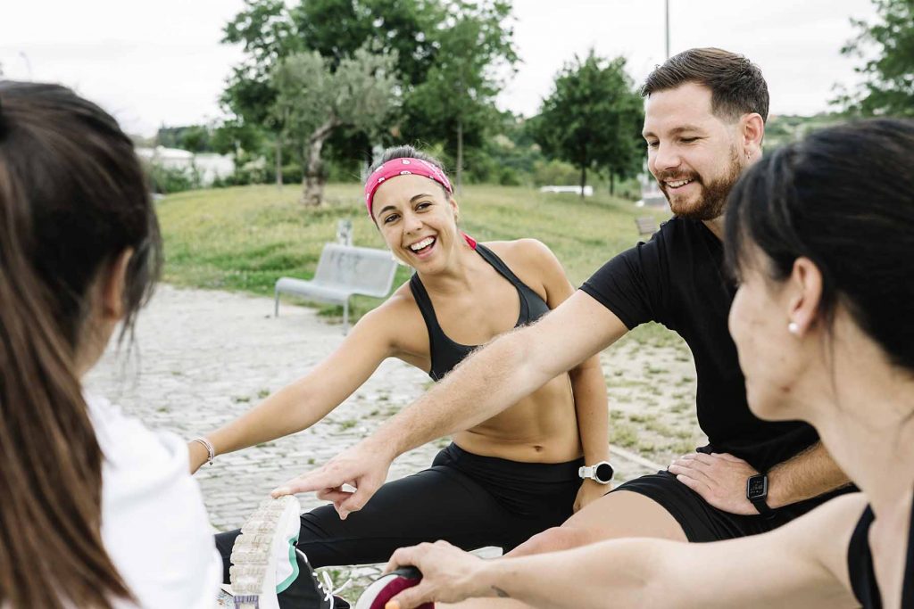 Group of happy people stretching outdoors after training