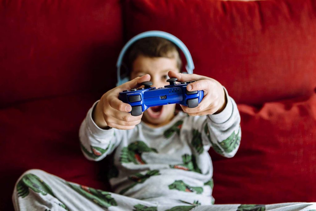 Boy wearing headphones while showing video game on sofa at home